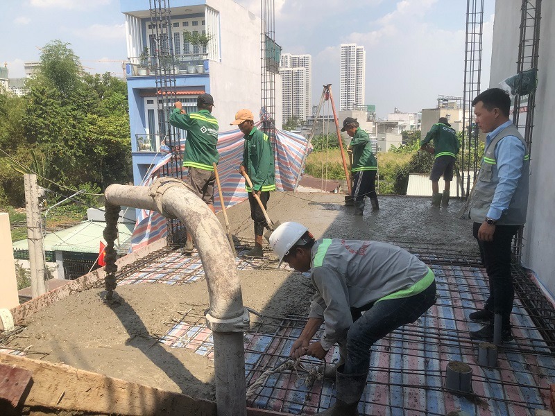 Thi Công Bê Tông Nhà Phố Chất Lượng, Đúng Kỹ Thuật Tại TP.HCM 3 Đội ngũ công nhân đang thực hiện công đoạn đầm dùi và làm phẳng bề mặt sàn bê tông tầng lầu